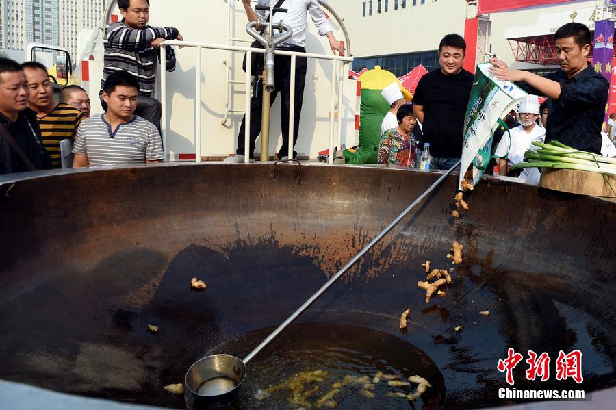 工作人員向大鍋內加入油和姜等烹飪調料。 圖片來源：CFP視覺中國