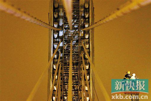 截至今日零時(shí)，男子仍未有下橋舉動(dòng)。圖為公安和消防人員乘消防云梯在高空上和男子交談。
