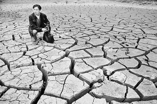 蹲在干涸的田地里，焦裕祿為饑餓的百姓揪心不已 《焦裕祿》劇照